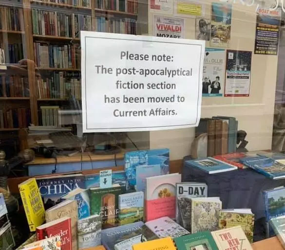 sign in bookstore window reading please note the post-apocalyptic fiction section has been moved to current affairs