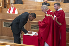 A new seminarian signs the covenant book at the 2023 "Red Mass" marking the start of a new academic year.
