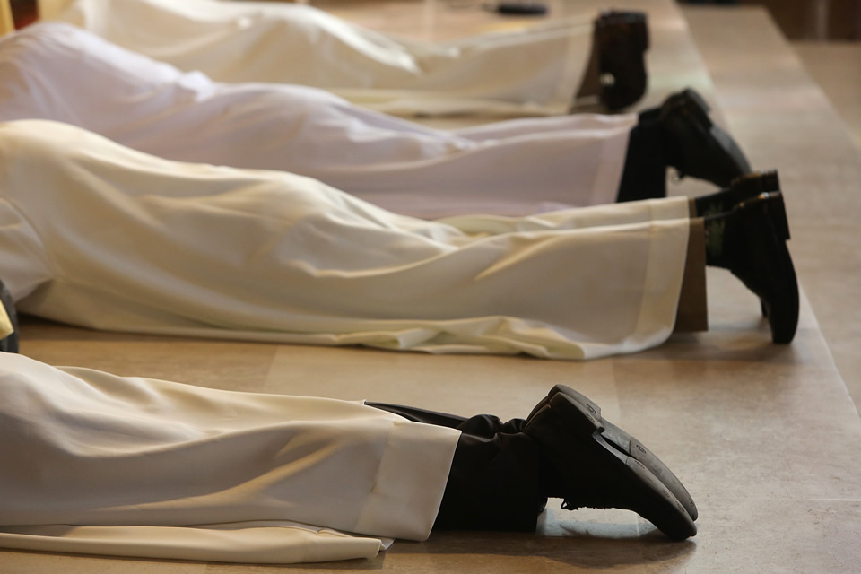 Ordinands lay prostrate in prayer during ordination rite.